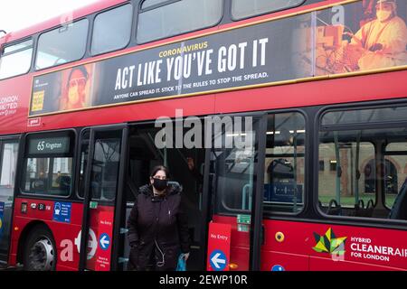 Kingston-upon-Thames, Großbritannien, 4th. Dezember 2020. Eine Frau, die eine Gesichtsmaske trägt, steigt aus einem Doppeldeckerbus aus, der eine Regierungsanbeterin trägt Stockfoto