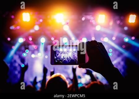 Hand mit dem Smartphone eingeschaltet, um aufzunehmen oder Bilder während des Live-Konzerts. Stockfoto