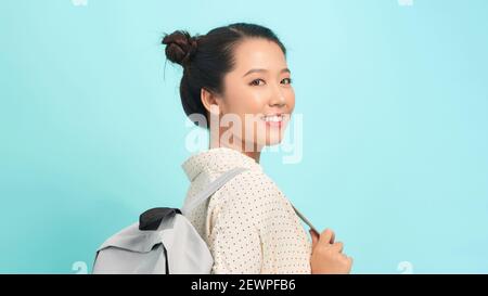 Junge Frau über isolierten blauen Hintergrund mit Rucksack Stockfoto