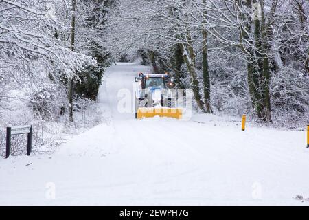 Traktor mit Schneepflug oder Pflug, der die Straße freilegt, Lymington Bottom Road, Medstead, Alton, Hampshire, England, Vereinigtes Königreich. Stockfoto