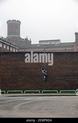 Reading, UK - 3. März 2021: Ansicht des Reading Prison mit einem Stück Street Art von Banksy zeigt einen Sträfling, der mit einem Stockfoto