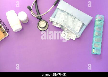 Blisterpackung, Thermometer und Stethoskop auf violettem Hintergrund Stockfoto