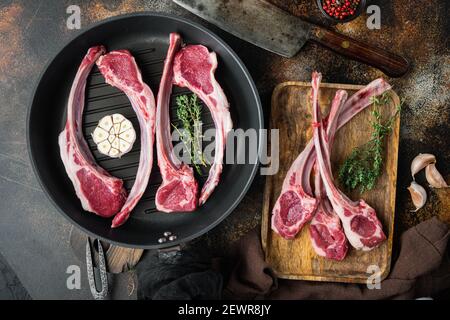 Gebratene rohe fettige Lammkoteletts Set, mit Zutaten, auf Braten Gusseisen Pfanne, auf alten dunklen rustikalen Hintergrund, Draufsicht flach legen Stockfoto