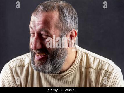 Porträt eines lächelnden grauen bärtigen Armeniers auf einem dunklen Grauer Hintergrund Stockfoto