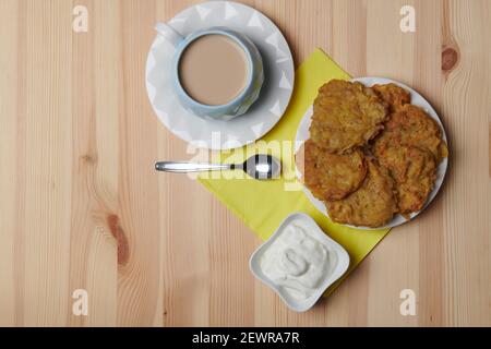 Kartoffelpfannkuchen auf einem Teller und eine Tasse Kaffee Auf einem hölzernen Hintergrund Stockfoto