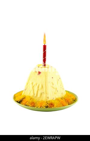 Quark-osterkuchen mit brennender roter Kerze Ein Teller mit gelben Löwenzahn Blüten isoliert auf weißem Hintergrund Stockfoto