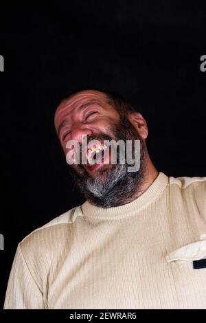Porträt eines lachenden grauen bärtigen Armeniers auf einem dunklen Grauer Hintergrund Stockfoto