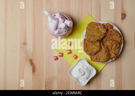 Kartoffelpfannkuchen auf einem Teller und eine Tasse Kaffee Auf einem hölzernen Hintergrund Stockfoto