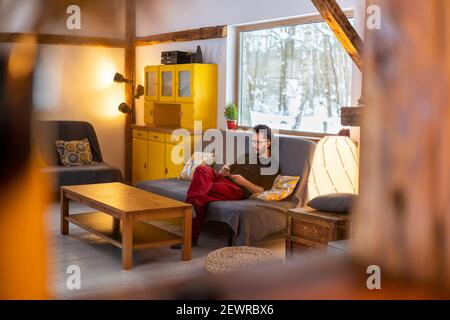 Junger Mann auf der Couch zu Hause sitzen, sie ihr Smartphone Stockfoto
