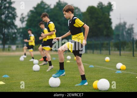 Teenage Boys Training Sports in a Row. Soccer Summer Camp für junge Jungen. Happy Football Spieler auf der Übungssitzung. Jugend-Team tritt Bälle auf Turf Stockfoto