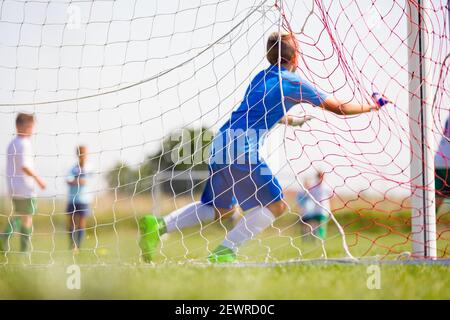 Fußball-Torhüter laufen und fangen Ball in einem Tor. Blick von hinten. Fußballnetz. Junge Jungen Treten Fußball-Spiel Stockfoto