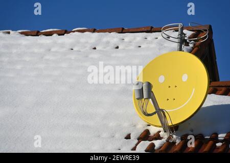 Leipziger Land, Deutschland. Februar 2021, 11th. Auf einem verschneiten Dach in Leipzig steht eine Satellitenschüssel mit Gesicht. Quelle: Volkmar Heinz/dpa-Zentralbild/ZB/dpa/Alamy Live News Stockfoto