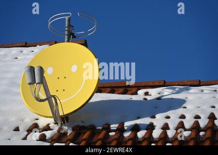 Leipziger Land, Deutschland. Februar 2021, 11th. Auf einem verschneiten Dach in Leipzig steht eine Satellitenschüssel mit Gesicht. Quelle: Volkmar Heinz/dpa-Zentralbild/ZB/dpa/Alamy Live News Stockfoto