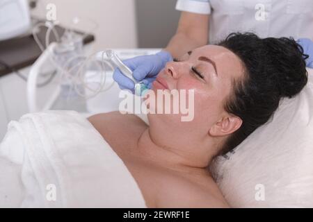 Charming plus size Frau bekommen Gesichtsmikrodermabrasion Behandlung auf sie Kinn im Schönheitssalon Stockfoto