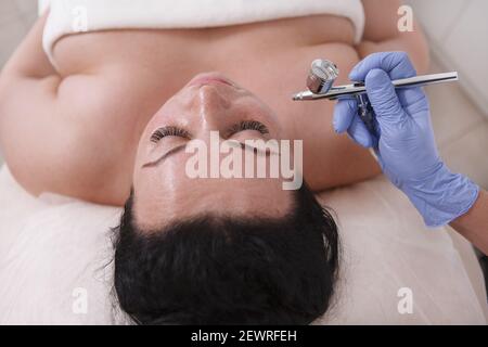 Draufsicht Nahaufnahme einer kurvigen Frau, die das Gesicht genießt Mikrodermabrasion im Schönheitssalon Stockfoto
