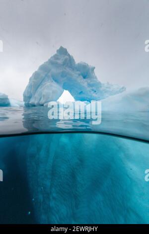 Über- und Unteransicht eines in einem Eisberg gebildeten Bogens auf Cuverville Island, Erra Channel, Antarktis, Polarregionen Stockfoto
