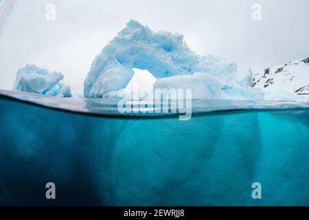Über- und Unteransicht eines in einem Eisberg gebildeten Bogens auf Cuverville Island, Erra Channel, Antarktis, Polarregionen Stockfoto
