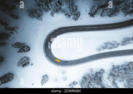 Luftaufnahme von Autos fahren auf Kurven der verschneiten Bergstraße im Winter, Schweiz, Europa Stockfoto