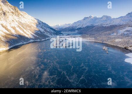 Schneebedeckte Berge umrahmen das Dorf Sils Maria und gefrorenen Sils See bei Sonnenaufgang, Luftbild, Engadin, Graubünden Kanton, Schweiz, Europa Stockfoto