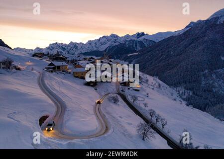 Autos fahren auf Kehren von verschneiten Straßen im Morgengrauen, Guarda, Unterengadin, Graubünden Kanton, Schweiz, Europa Stockfoto