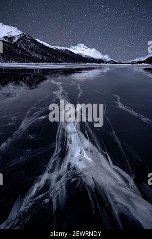 Sternenhimmel über dem geknackten Eis am gefrorenen Silvaplana-See im Winter, Maloja, Engadin, Kanton Graubünden, Schweiz, Europa Stockfoto