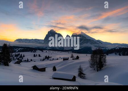 Mit Schnee bedeckte Berghütten mit Langkofel und Langkofel im Hintergrund bei Sonnenaufgang, Seiser Alm, Dolomiten, Südtirol, Italien, Europa Stockfoto