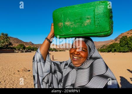 Frau, die einen Wasserbehälter auf dem Kopf trägt, Oase von Timia, Luftberge, Niger, Afrika Stockfoto