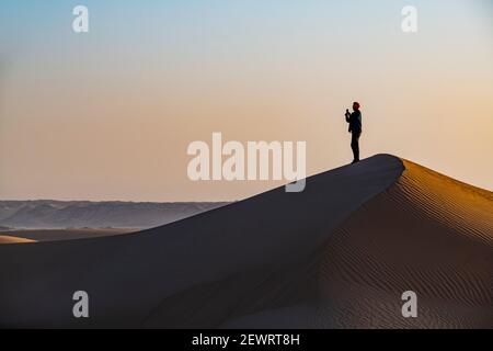 Mann wandern durch die Sanddünen, Dirkou, Djado Plateau, Sahara, Niger, Afrika Stockfoto