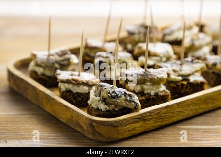 Kleine Vorspeisen mit Fischkonserven und Frischkäse Holztablett auf Tischhintergrund Stockfoto