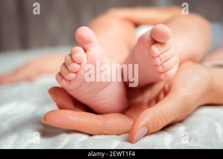 Die Hand einer Mutter hält die Beine des Babys. Nahaufnahme. Das Ende von Muttertag und Elternschaft. Stockfoto