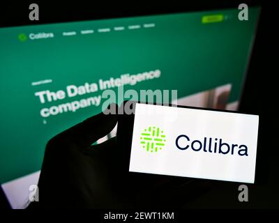 Person, die Smartphone mit Logo des belgischen Software-Unternehmens Collibra NV auf dem Bildschirm vor der Website hält. Konzentrieren Sie sich auf die Telefonanzeige. Nicht modifiziertes Foto. Stockfoto