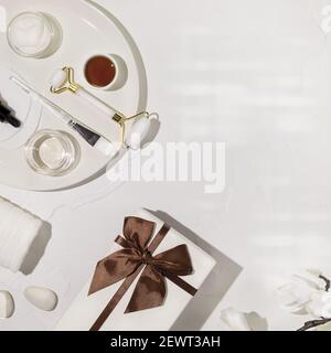 Flach Lay, weiß, kosmetische Zusammensetzung mit natürlichen Inhaltsstoffen, Beauty-Accessoires, Geschenk-Box und Magnolien-Blumen. Hautpflege Lifestyle-Konzept. Fac Stockfoto