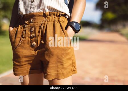 Mittelteil einer afroamerikanischen Frau, die mit Händen in ihr steht Taschen in einem Park Stockfoto