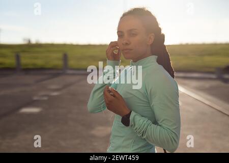afroamerikanische Frau konzentriert, trägt Sportkleidung Sport im Park trainieren setzen Kopfhörer in Stockfoto