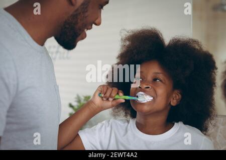 afroamerikanisches Mädchen und ihr Vater Zähneputzen zusammen Stockfoto