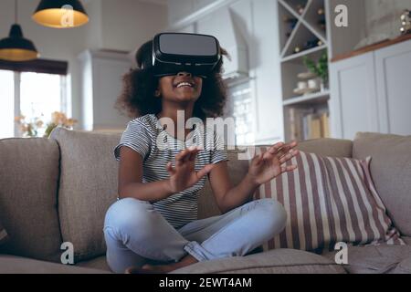 Afroamerikanische Mädchen sitzen im Wohnzimmer mit vr Headset Stockfoto