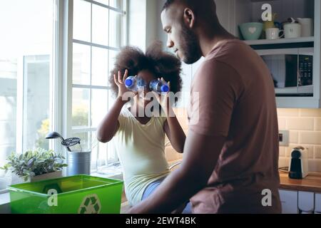 afroamerikanisches Mädchen und ihr Vater sortieren Recycling zusammen in Küche Stockfoto