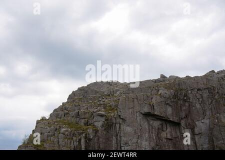 Schöne Details der zerklüfteten Felswand gegen den hellen bewölkten Himmel im Hintergrund bei Preikestolen in Norwegen. Stockfoto