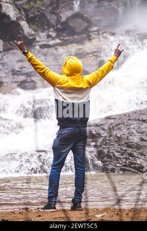 Kookal, Indien - 21st. Februar 2021: Asiatischer Mann steht in der Nähe von Wasserfällen. Redaktionelles Material. Stockfoto