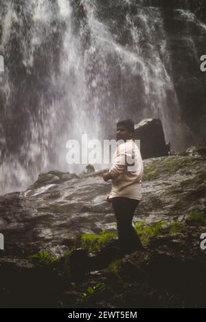 Kookal, Indien - 21st. Februar 2021: Asiatischer Mann steht in der Nähe von Wasserfällen. Redaktionelles Material. Stockfoto