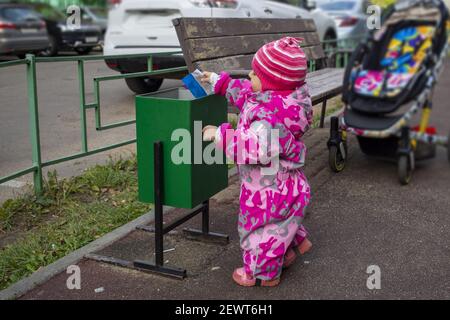 Entzückendes Kind wirft Müll in einen Straßeneimer Stockfoto