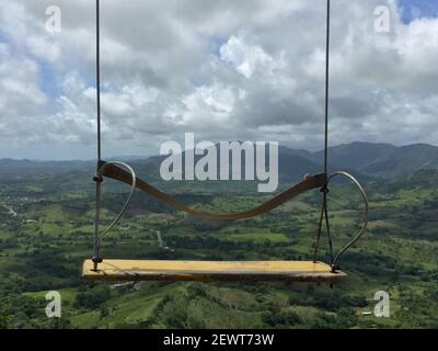 Eine Nahaufnahme einer Schaukel auf der Spitze von Montana Redonda in der Dominikanischen Republik mit einer tropischen Landschaft Stockfoto