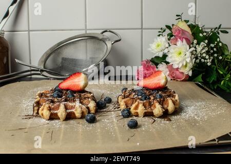 Zwei Waffeln mit Erdbeeren und Heidelbeeren mit Puderzucker auf IT Stockfoto