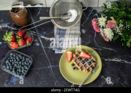 Ein Blick von oben auf eine Waffel mit Erdbeeren und Heidelbeeren Mit Puderzucker darauf Stockfoto