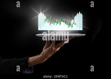 Business man hält Tablet und zeigt holographische Grafiken und Börsenstatistiken Gewinne. Konzept der Wachstumsplanung und Geschäftsstrategie Stockfoto