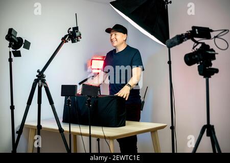 Ein Content Creator entboxt vor seinen Kameras und Lichter in seinem Studio Stockfoto