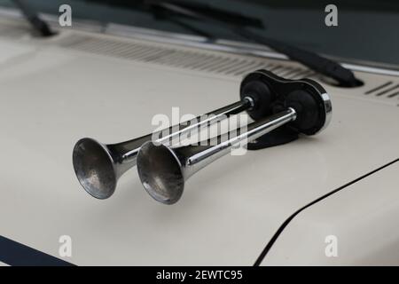 Nahaufnahme von zwei glänzenden Metallhörnern auf weißem Auto. Stockfoto