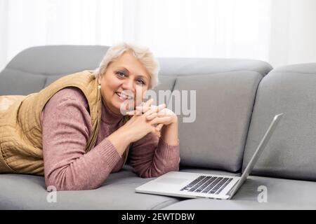 Serious reifen älteren erwachsenen Frau beobachten Training Webinar auf Laptop arbeiten von zu Hause oder im Büro. 60s Geschäftsfrau mittleren Alters, die Notizen während Stockfoto