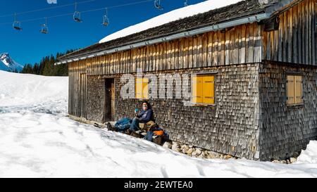 Pause auf der Bank an einer geschindelten Alphütte. Pause auf der Bank bei einer Schindelhütte. Wintersport in Österreichs verschneiten alpen. Schneeschuh Stockfoto