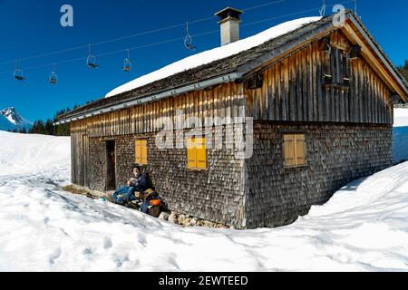 Verschneite Berge mit Schindelhütte, Geschindelte Hütte, Skigebiet Saloberkopf mit dem Karhorn im Hintergrund. Wintersport am Körbersee, Österreich Stockfoto